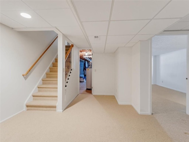 finished basement with stairs, carpet flooring, a paneled ceiling, and baseboards