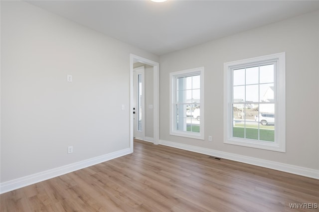 spare room featuring light wood-type flooring, baseboards, and visible vents