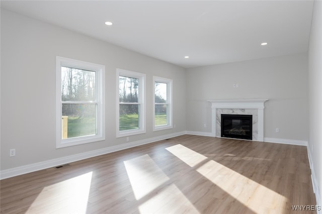 unfurnished living room featuring baseboards, a high end fireplace, visible vents, and recessed lighting