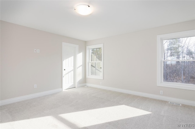 unfurnished room with baseboards, visible vents, and light colored carpet