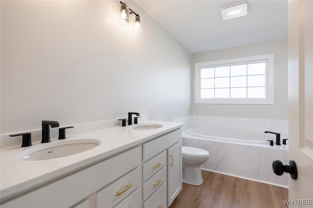 full bath featuring a garden tub, wood finished floors, a sink, and toilet