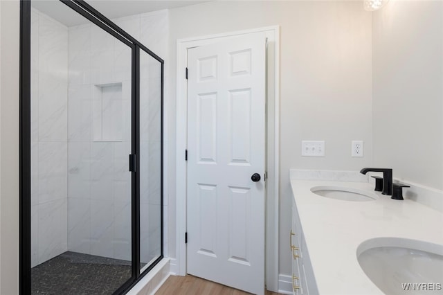 full bath with a stall shower, wood finished floors, a sink, and double vanity