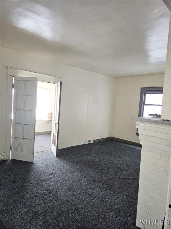 spare room featuring baseboards and dark colored carpet