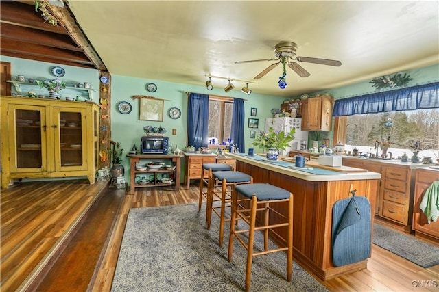 kitchen featuring brown cabinetry, a kitchen island, light countertops, and wood finished floors