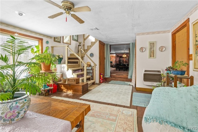 interior space featuring a textured ceiling, visible vents, a ceiling fan, stairs, and heating unit