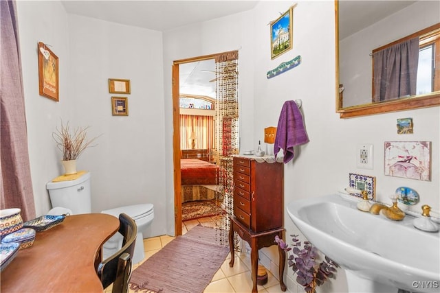 ensuite bathroom featuring toilet, tile patterned flooring, a sink, and ensuite bathroom