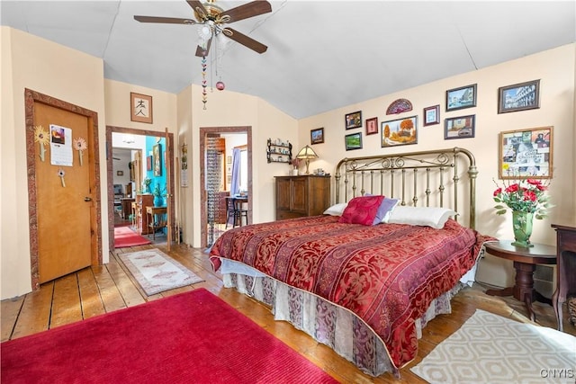 bedroom with a ceiling fan, vaulted ceiling, and wood finished floors