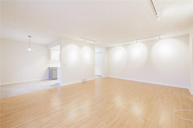 interior space with light wood-style flooring, track lighting, visible vents, and baseboards