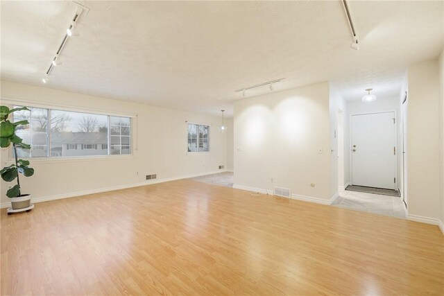 unfurnished room with visible vents, wood finished floors, and rail lighting