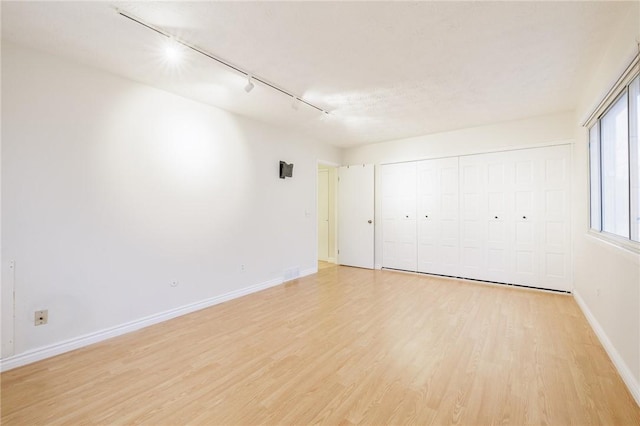 unfurnished room featuring rail lighting, light wood-style flooring, and baseboards