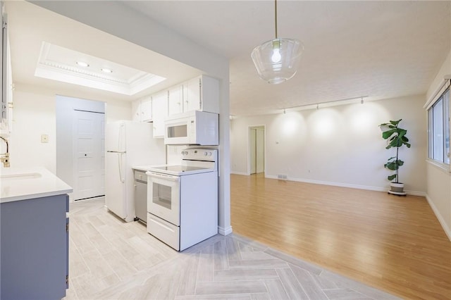 kitchen featuring light wood-type flooring, light countertops, white appliances, and a raised ceiling