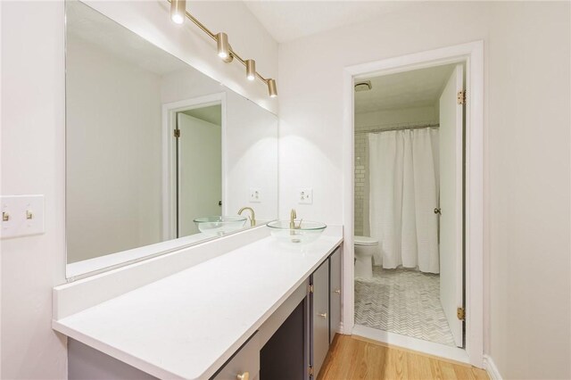 bathroom featuring toilet, a shower with shower curtain, wood finished floors, visible vents, and vanity