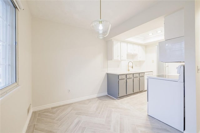 kitchen featuring stove, baseboards, light countertops, washer / clothes dryer, and a raised ceiling