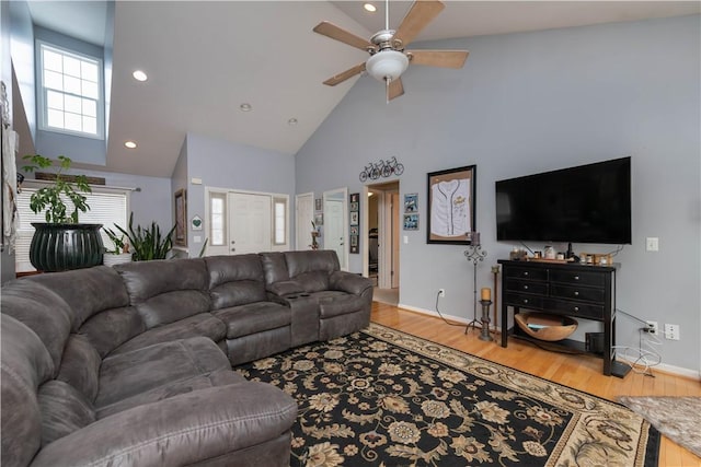 living room featuring ceiling fan, high vaulted ceiling, light wood-style flooring, and baseboards