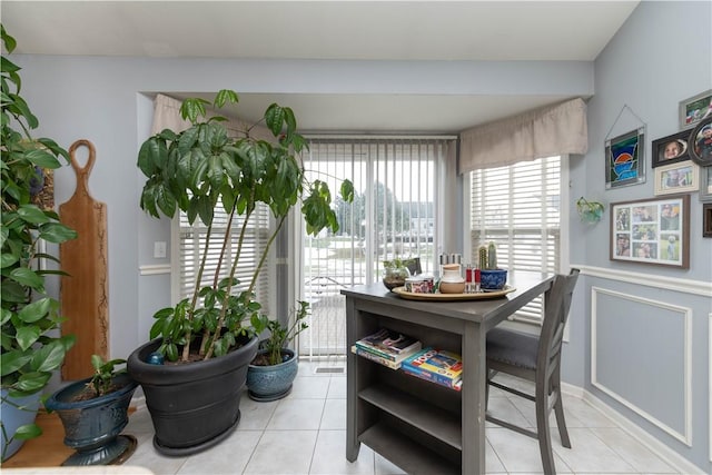 dining room with wainscoting, a decorative wall, and light tile patterned floors