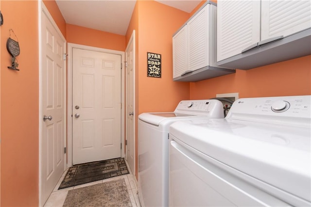 laundry room featuring light tile patterned floors, washing machine and clothes dryer, and cabinet space