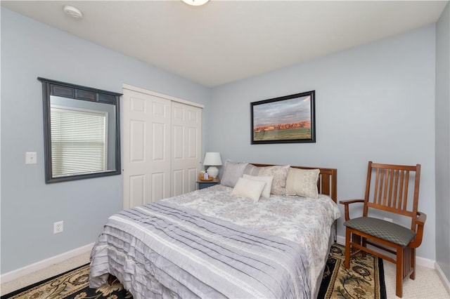 carpeted bedroom featuring baseboards and a closet