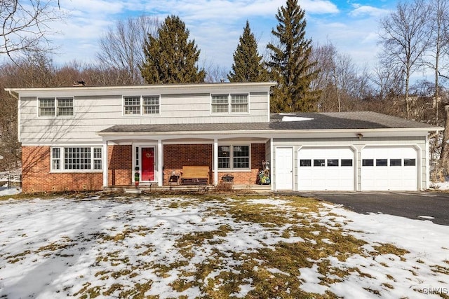 traditional-style house with an attached garage, covered porch, aphalt driveway, and brick siding