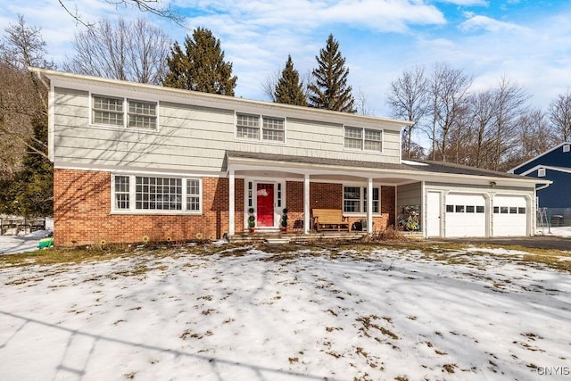 traditional home with an attached garage, covered porch, aphalt driveway, and brick siding