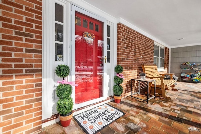 property entrance with covered porch and brick siding