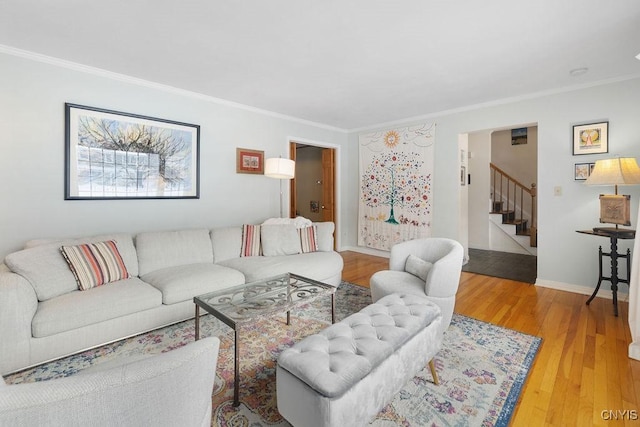 living area featuring crown molding, light wood-style flooring, baseboards, and stairs