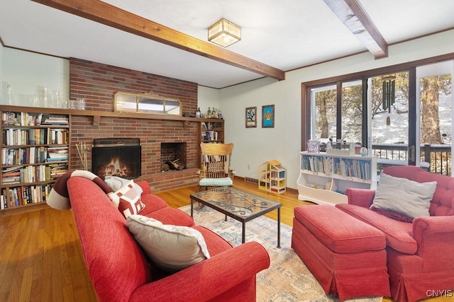 living area featuring beam ceiling, a fireplace, baseboards, and wood finished floors