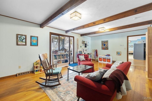 living room with light wood-type flooring, baseboards, visible vents, and beamed ceiling