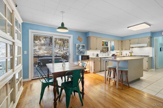 dining space featuring light wood-type flooring, crown molding, and baseboards