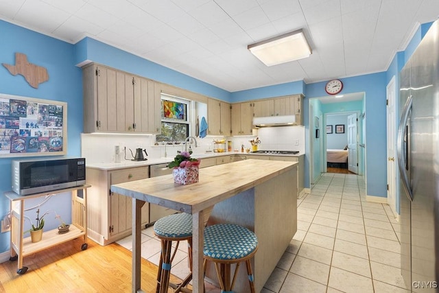 kitchen with tasteful backsplash, appliances with stainless steel finishes, ornamental molding, under cabinet range hood, and light tile patterned flooring