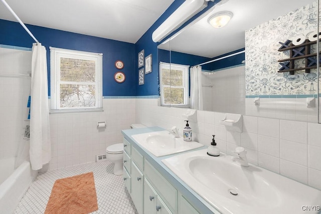 full bath featuring a wainscoted wall, tile walls, toilet, shower / bath combo, and tile patterned flooring