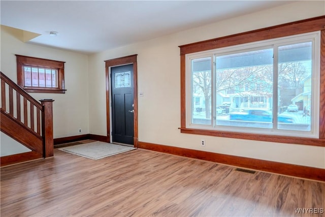 entrance foyer with stairs, light wood-style flooring, visible vents, and a wealth of natural light