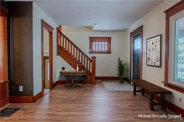 foyer entrance with stairs, wood finished floors, visible vents, and baseboards