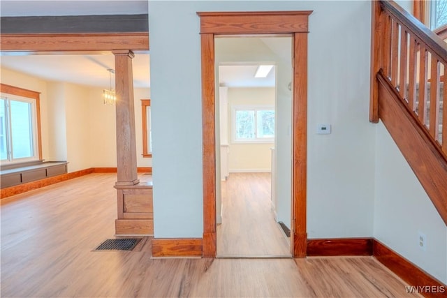 interior space with wood finished floors, visible vents, baseboards, stairway, and ornate columns