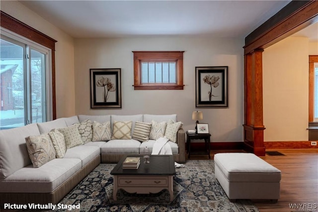 living room featuring baseboards, wood finished floors, and a healthy amount of sunlight