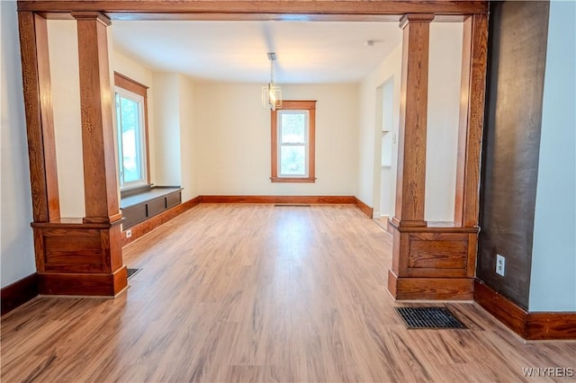 interior space featuring baseboards, decorative columns, visible vents, and wood finished floors