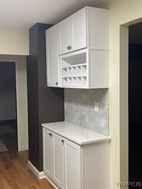 kitchen featuring open shelves, wood finished floors, decorative backsplash, white cabinetry, and light stone countertops