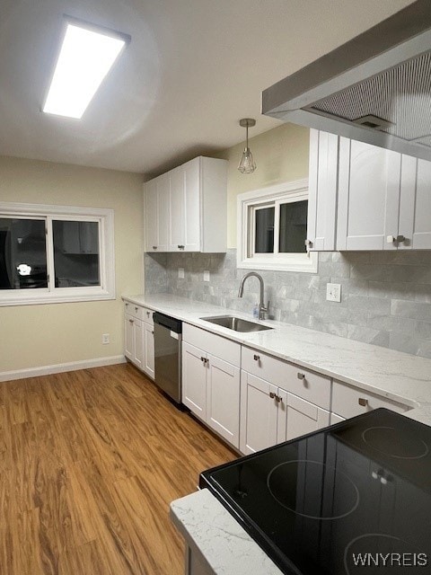 kitchen with stainless steel dishwasher, light wood-style floors, white cabinetry, a sink, and exhaust hood