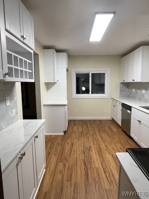 kitchen with tasteful backsplash, dishwasher, wood finished floors, light stone countertops, and white cabinetry