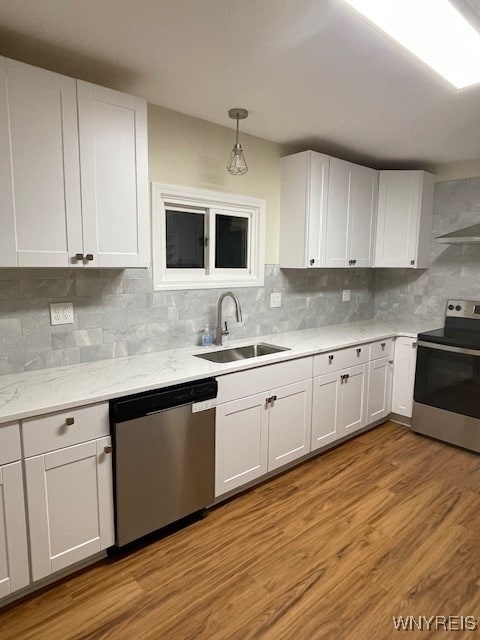 kitchen featuring light wood finished floors, stainless steel appliances, tasteful backsplash, white cabinetry, and a sink