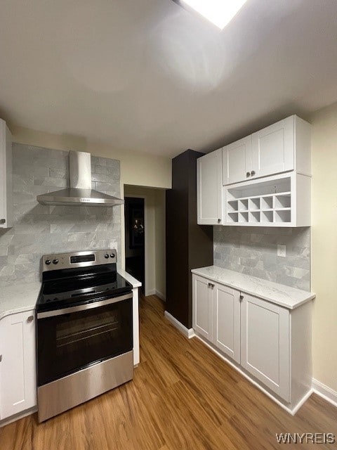 kitchen with wall chimney exhaust hood, light wood-style floors, decorative backsplash, and stainless steel electric stove