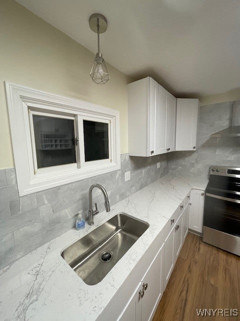 kitchen with white cabinets, a sink, backsplash, and stainless steel electric range