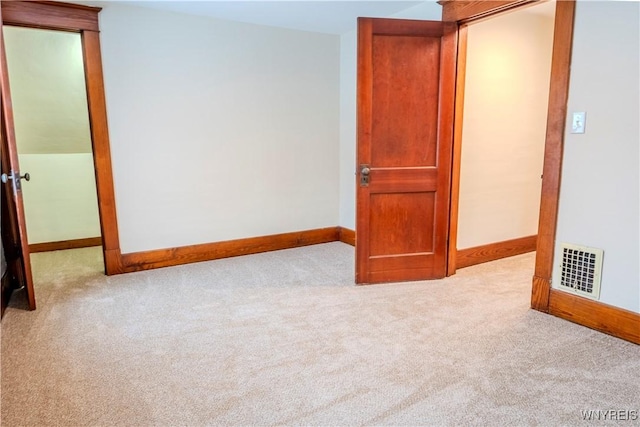 carpeted spare room with visible vents and baseboards