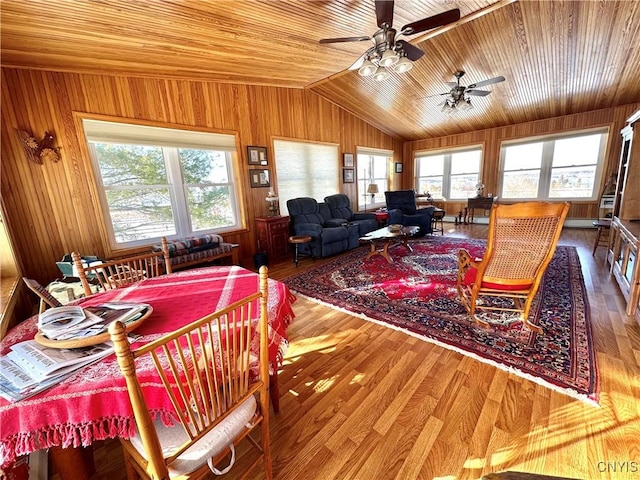 dining space with lofted ceiling, wood ceiling, wood walls, and wood finished floors