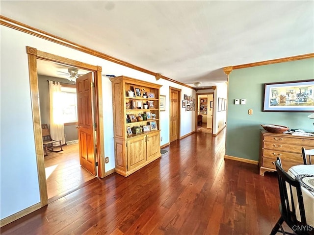 hallway featuring dark wood-style floors, baseboards, and ornamental molding