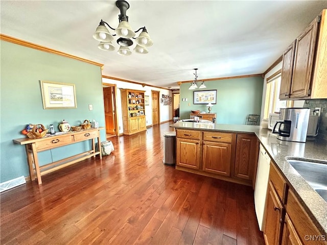 kitchen with a peninsula, ornamental molding, brown cabinets, and dark wood-type flooring