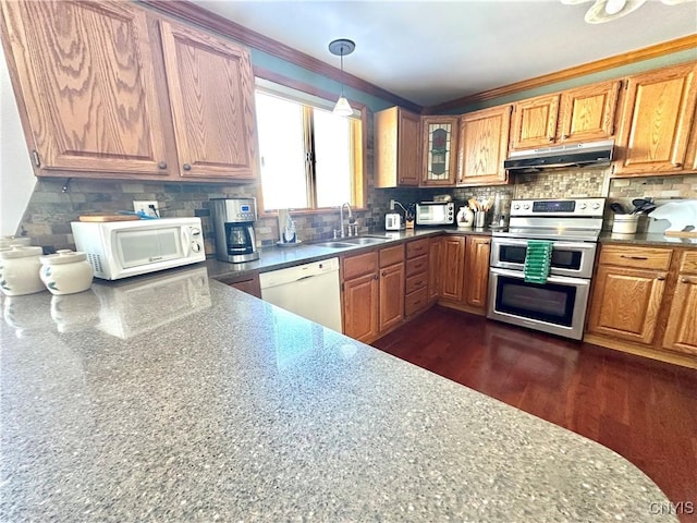 kitchen featuring white appliances, under cabinet range hood, decorative backsplash, and a sink