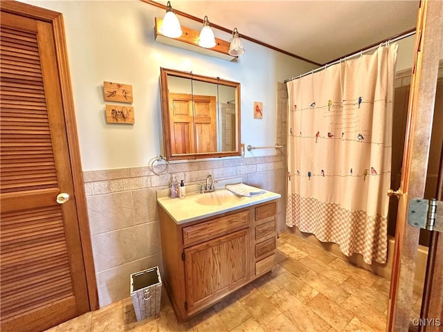 full bathroom featuring a wainscoted wall, a shower with curtain, tile walls, and vanity