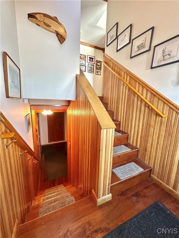 staircase featuring a wainscoted wall, wood walls, and hardwood / wood-style flooring