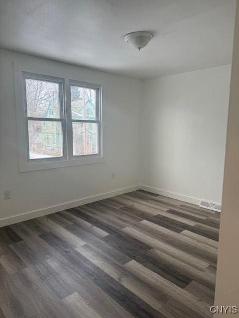 spare room featuring dark wood finished floors, visible vents, and baseboards