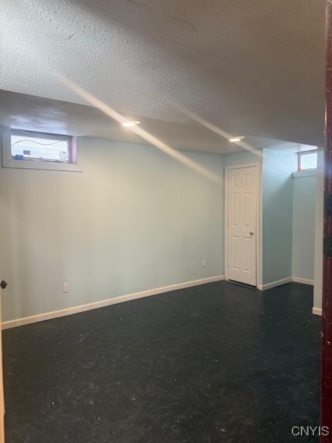 below grade area featuring a textured ceiling and baseboards